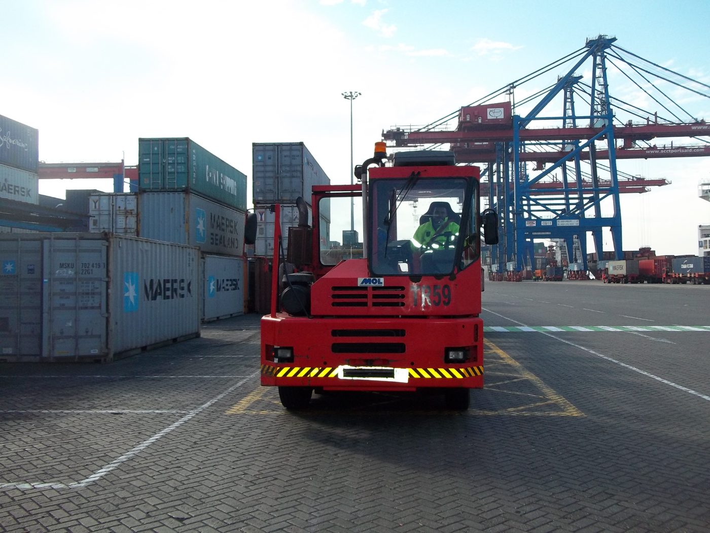 Trade Mar transportation team, terminal tractor moving containers beneath the cranes